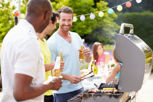 Men visiting and cooking on grill outside.